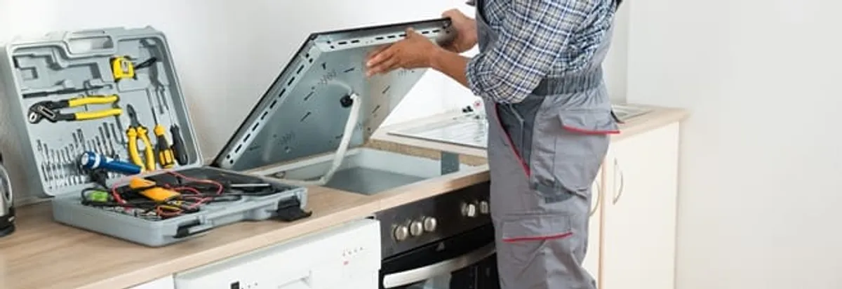 Cooktop repair technician lifting a built-in stovetop for service in San Jose, CA