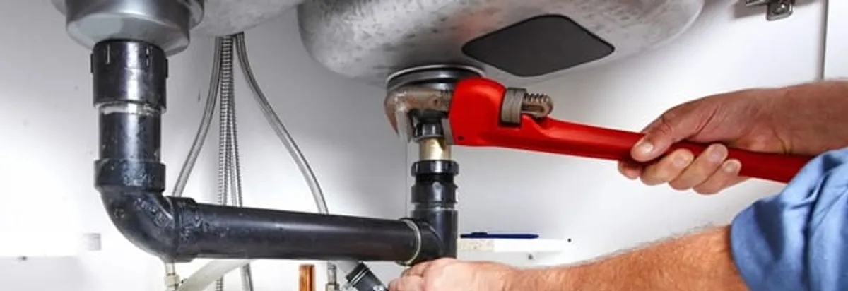 Garbage disposal repair technician tightening the sink drain and disposal connection in San Jose, CA