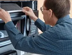 Appliance repair technician replacing a microwave vent filter in San Jose, CA