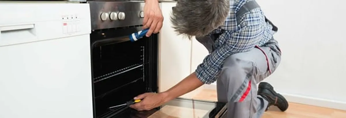Oven repair technician inspecting and servicing an electric oven in San Jose, CA