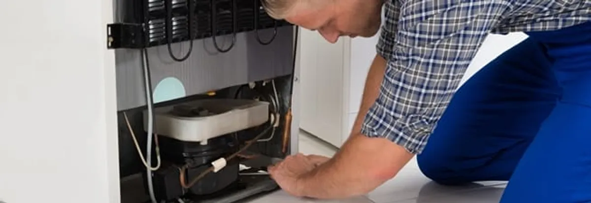 Refrigerator repair technician servicing the compressor and condenser area in San Jose, CA