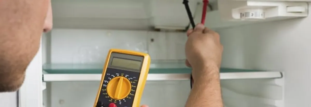 Refrigerator repair technician testing electrical components with a multimeter in San Jose, CA