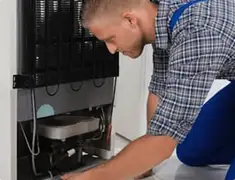 Refrigerator repair technician servicing the compressor and condenser area in San Jose, CA