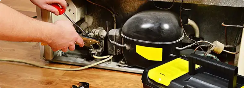 Refrigerator repair technician fixing the compressor and wiring in San Jose, CA